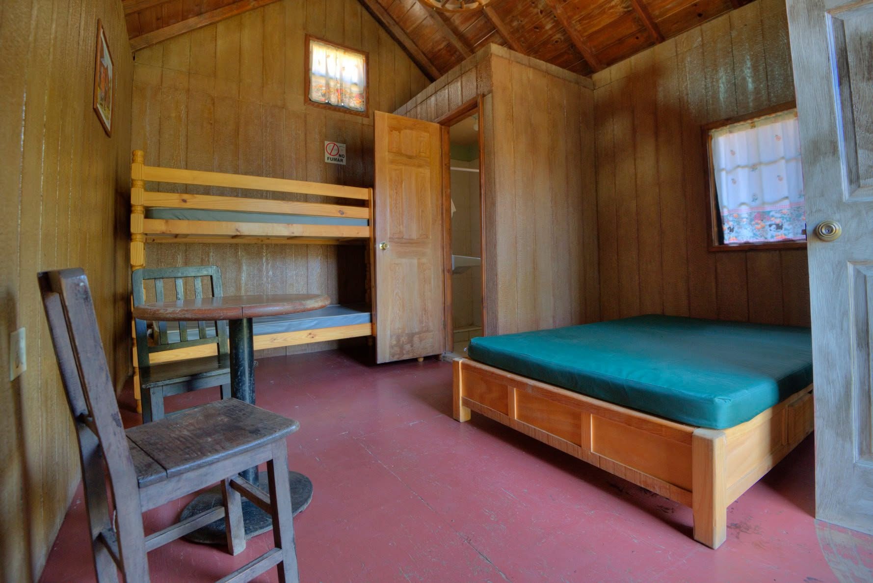 Interior de una cabaña con cama matrimonial y litera